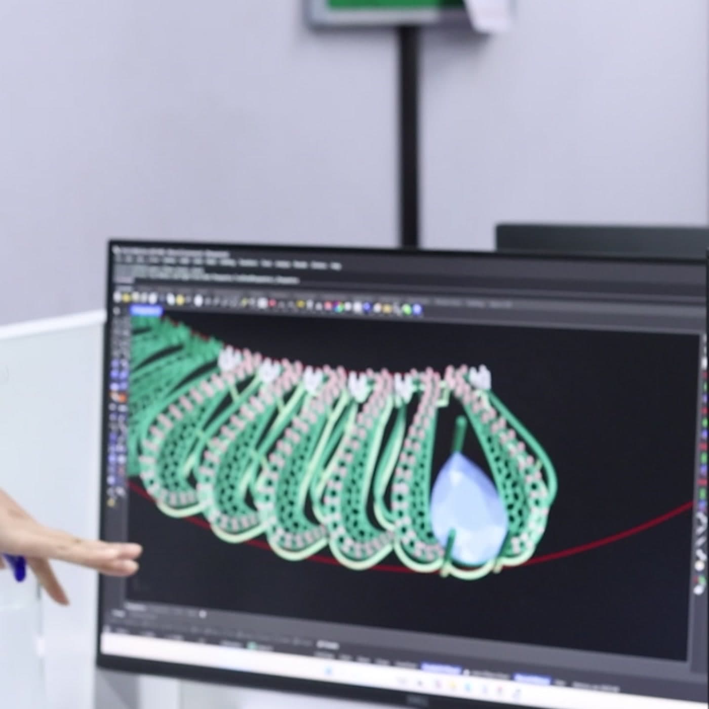 A CAD model of an emerald necklace on screen, reviewed by the design team