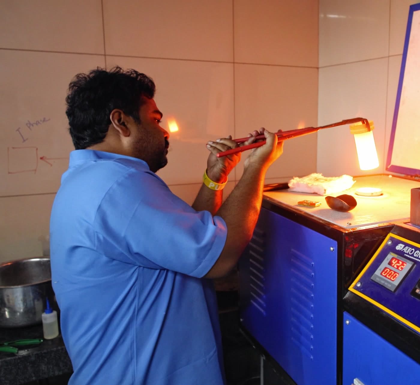 A craftsman at the casting station, heating metal with a torch