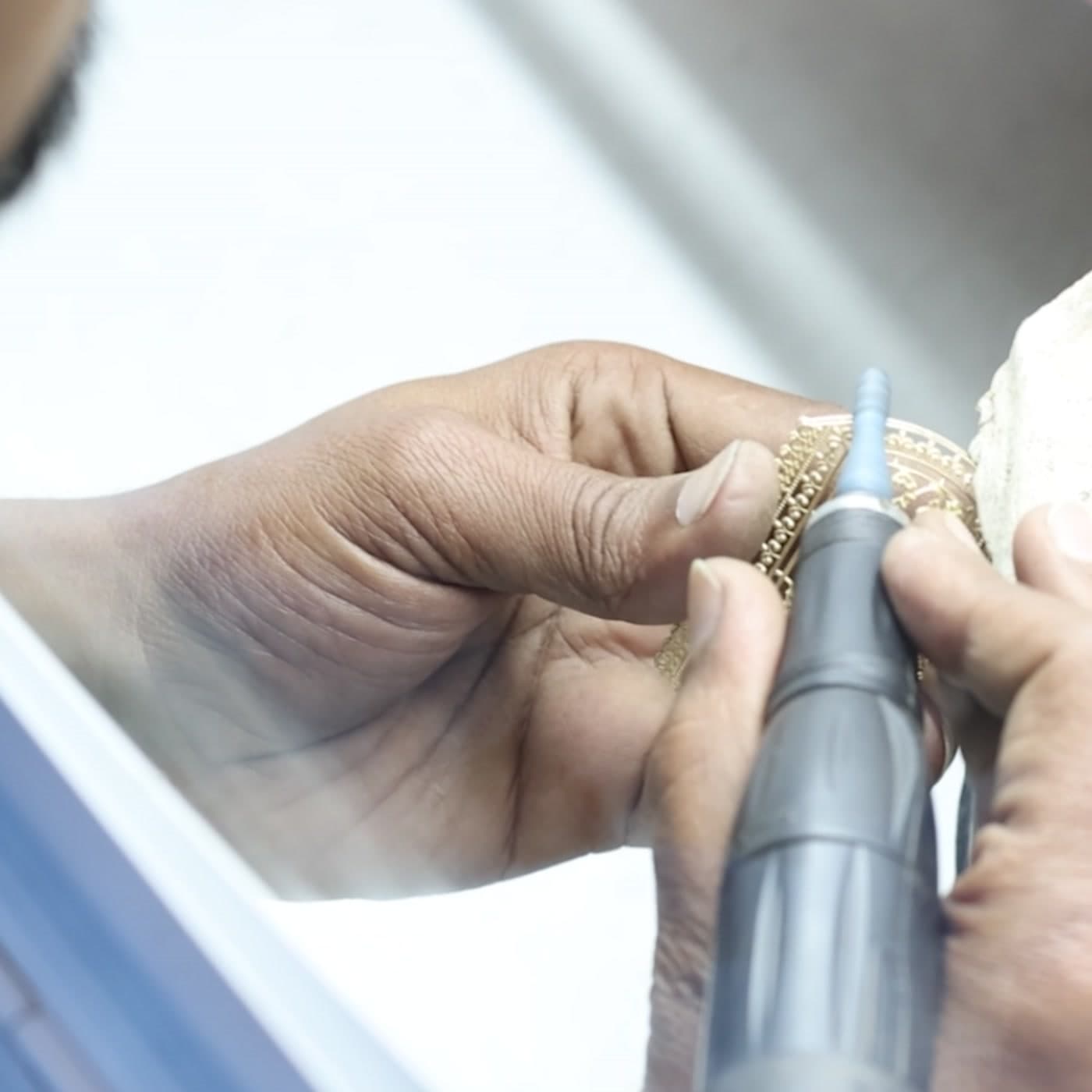 Close-up of a gold piece being polished by hand